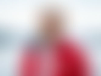 Arnt Inge Gjerde wearing a VARD hard hat and red jacket, standing by the fjord.