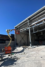 Plataforma articulada trabajando en exterior de bodega industrial