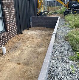 Drainage gravel backfilling behind a newly installed charcoal concrete sleeper retaining wall in Newcastle.