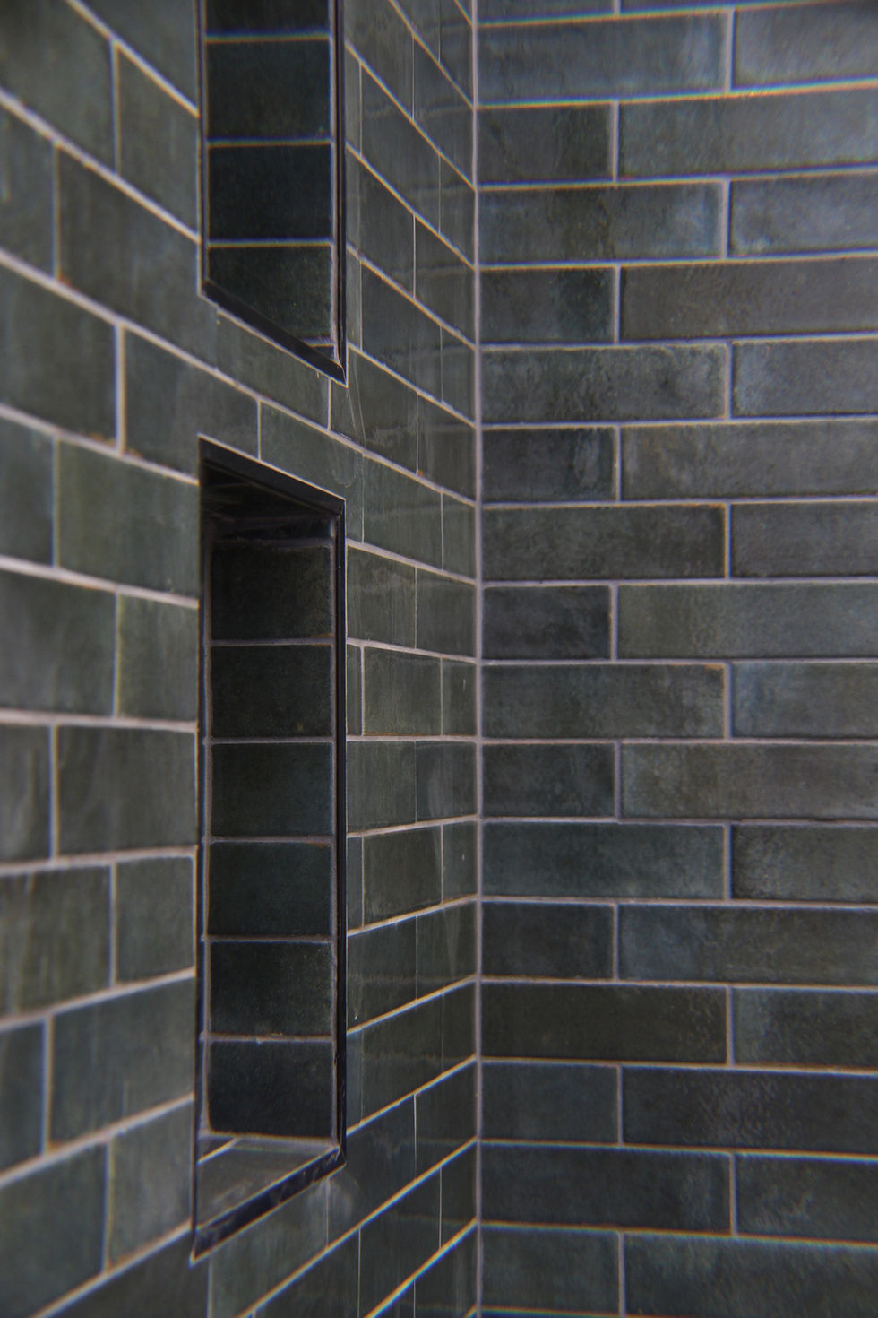 Two built-in niches with green 2x8 tiles in a contemporary walk-in shower