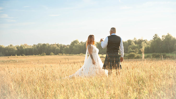 couple de mariés discutant dans un champ de blé ensoleillé.