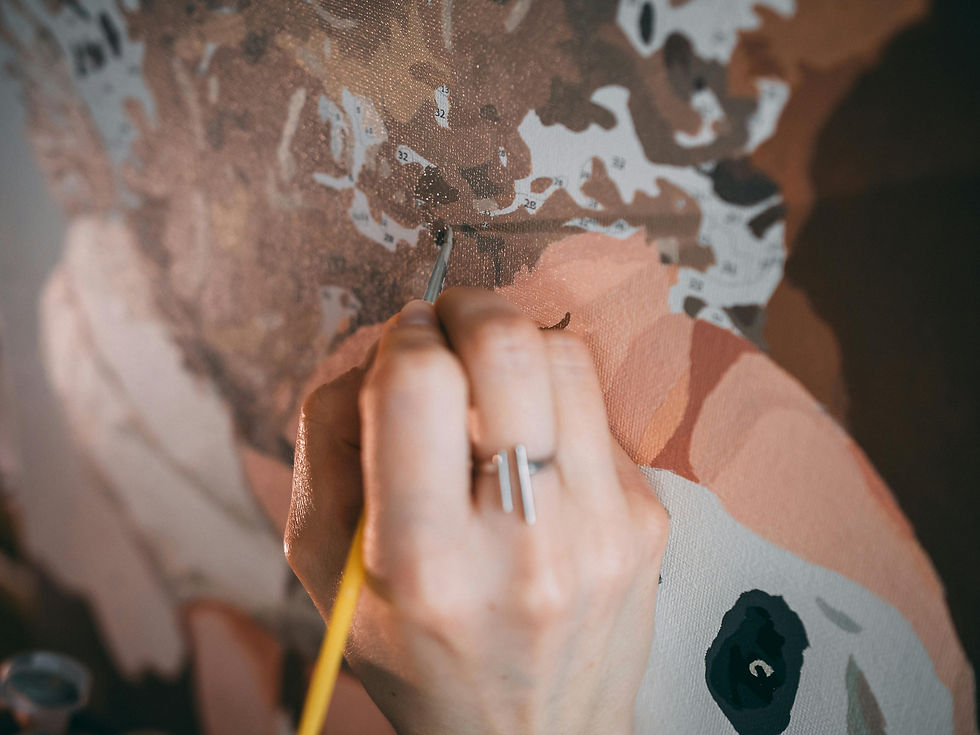 Hand painting a paint-by-numbers canvas with a fine brush, focusing on detail.