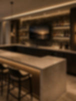Modern home bar with stone counters and backlit shelving.