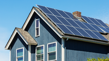 A blue house with newly installed solar panels on its roof.