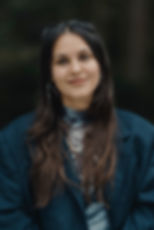 Lächelnde junge Frau mit dunklem Haar und blauem Sakko
