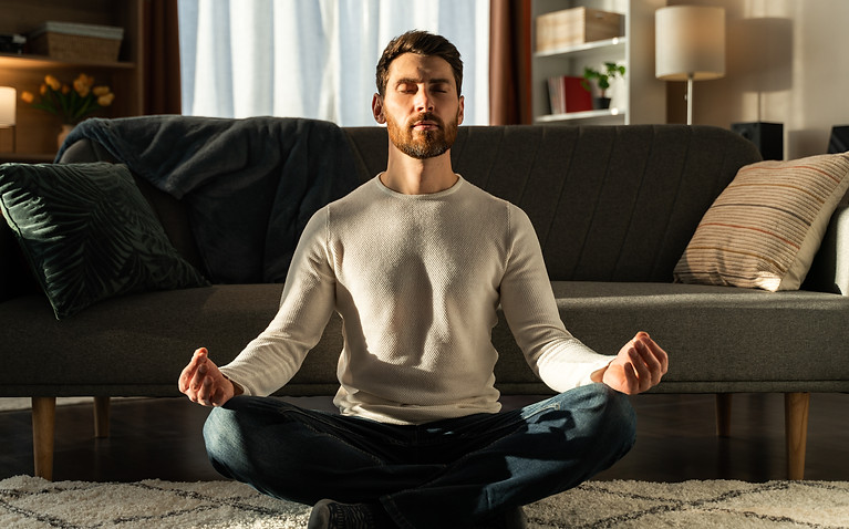 caucasian-man-meditating-lotus-pose-with-closed-eyes-home-sport-fitness-healthy-lifestyle-