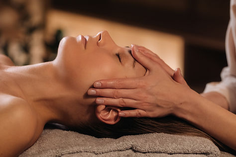 A cosmetologist girl does a facial and neck massage to a girl in the office for skin elast