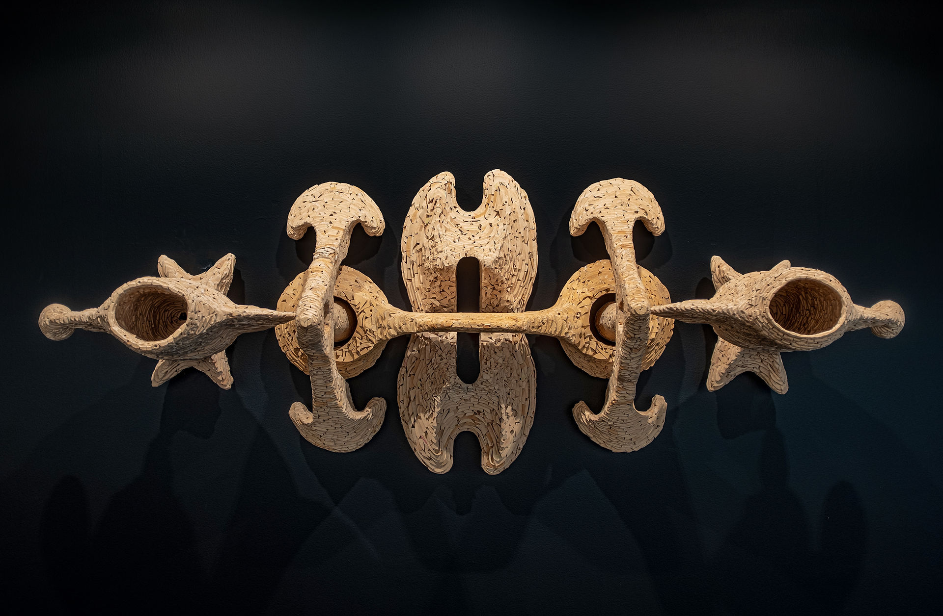 Robert Mirek's handcrafted Wood Sculpture hangs on a wall in a Metro Detroit art gallery, titled "Mitosis No. 607"
