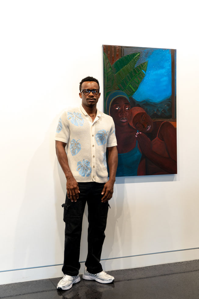 Artist standing in front of Sisters painting in a gallery.