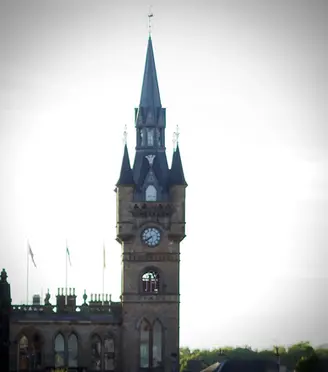 Clock tower with clock and flags in front of a bright sky