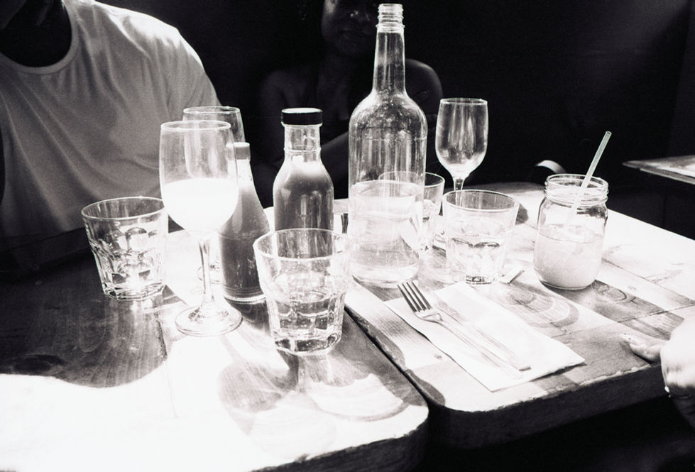 Black and white restaurant table setting with water, sauce bottles, glasses.