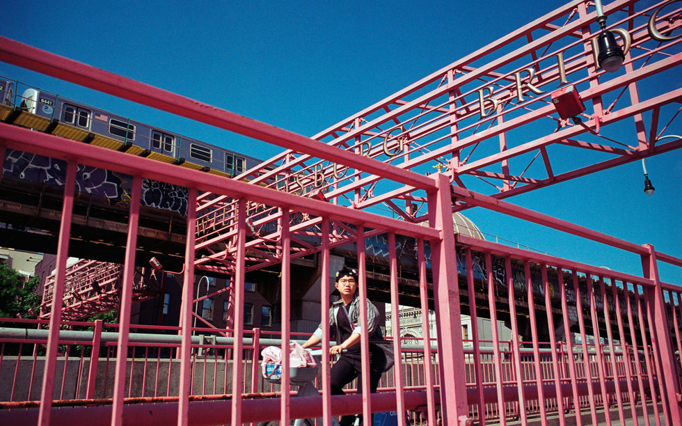 Person on pink bridge with train in background.