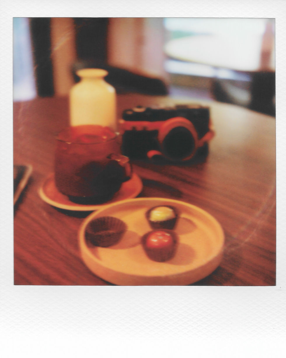 Blurry image of coffee, chocolates, and a camera.