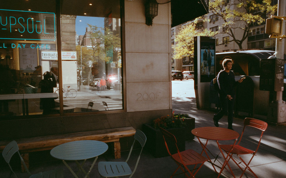 Street view with chairs and a window reflection.
