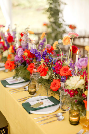 A formal table setting with colorful summer flowers as the centerpiece