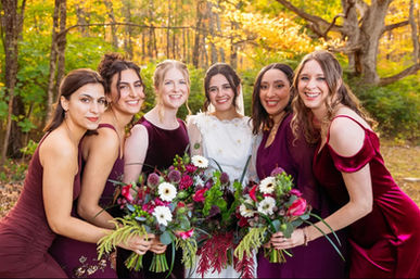 A bride and bridesmaids with burgundy and green Christmas themed bouquets