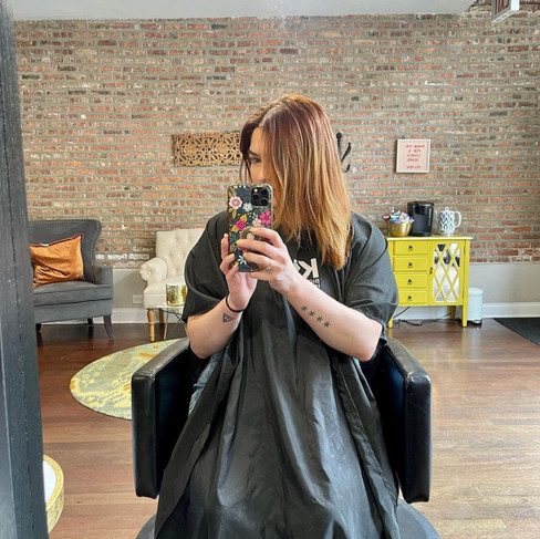A brunette girl sitting in a hair salon chair before her hair appointment