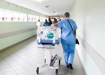 Hospital worker in a hallway pushing a trolly from the NICU