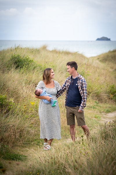 Mother and father walking with baby in beach, Rock, Cornwall, UK
