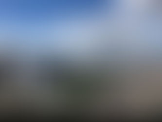 A low-angle view of sleek, modern skyscrapers reaching toward a bright blue sky filled with white, fluffy clouds.