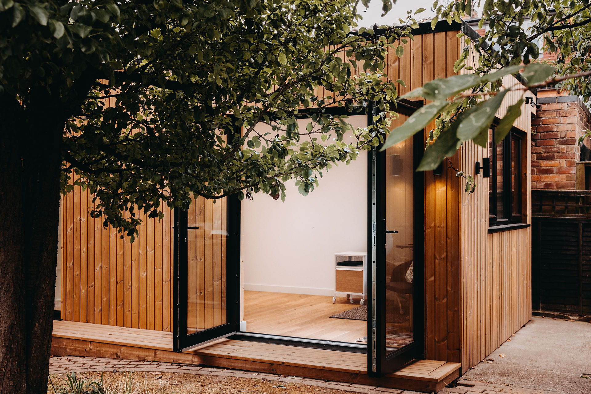 Wooden home office with doors open looking into office space, wooden panels surrounding