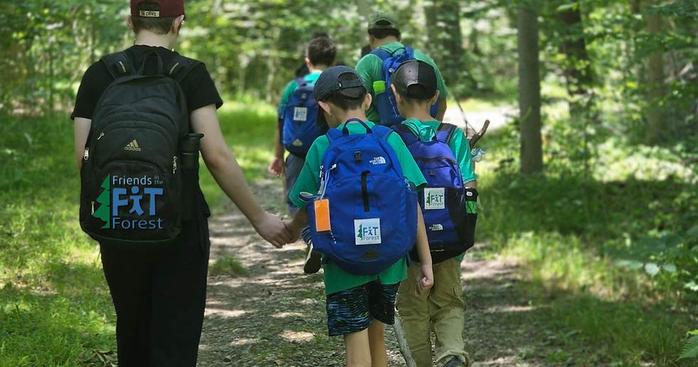 Counselor in Training (CIT) holding a camper’s hand during Friends in the Forest Social Skills Camp, supporting connection and engagement during an outdoor camp activity.