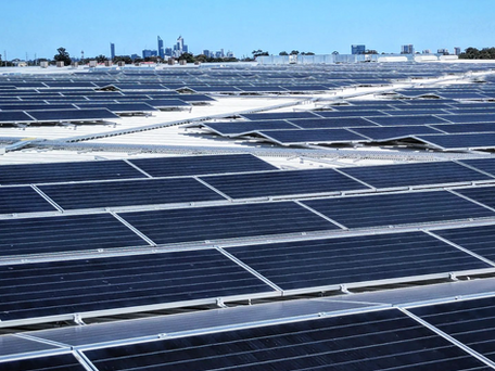 A large array of solar panels with a city skyline in the background