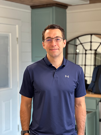 General contractor standing in front of some cabinets and and mirror.