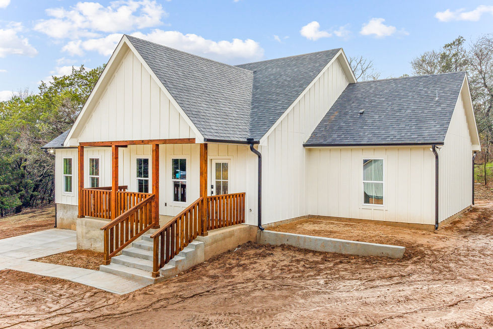 a white house with a black roof and a wooden porch