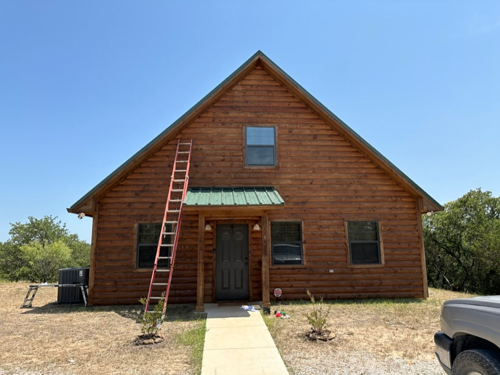 the front of a log cabin with a ladder leaning against it