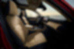 2026 Mazda CX-5 Beige leather car interior with a touchscreen display, viewed from the passenger side. Sunroof open, overlooking a serene water landscape.