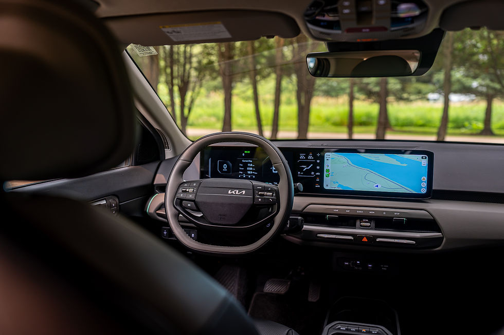 2026 KIA EV4 Wind Premium - Modern Kia car interior with digital dash and Google Maps navigation, parked by trees outside the windshield.