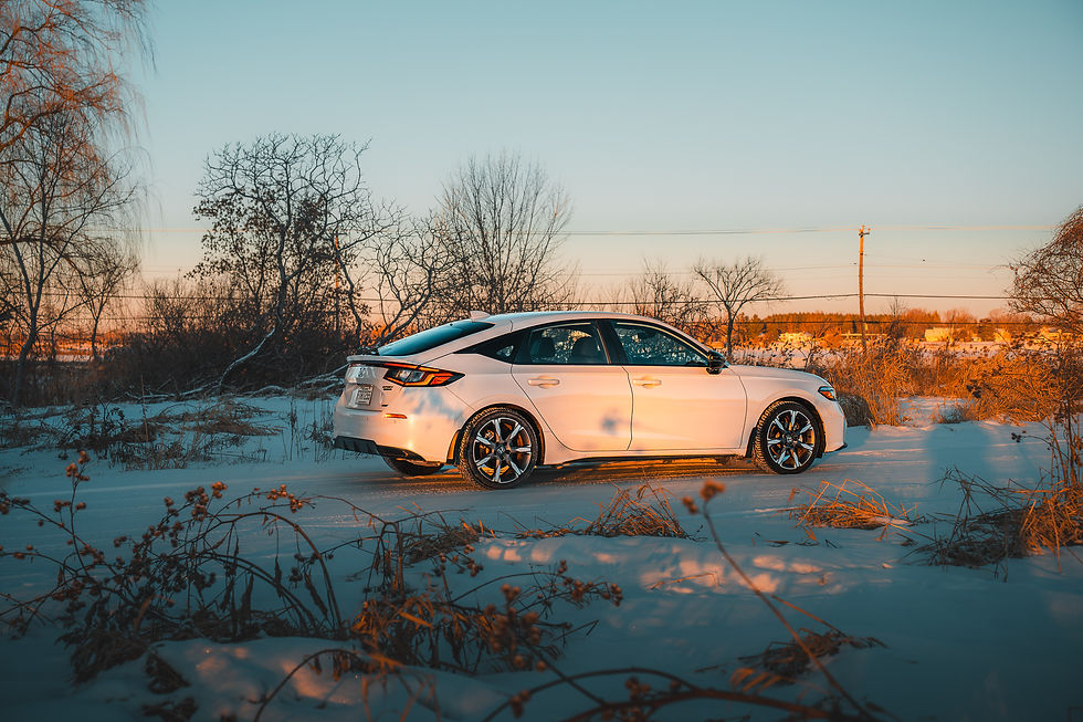 Honda Civic Hybrid - White car parked on a snowy terrain during sunset. Bare trees and a golden light create a warm contrast with the winter landscape.