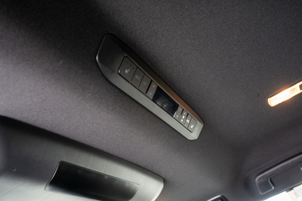 Toyota Sienna Hybrid - Car roof console with black buttons and warm overhead lights, viewed close up against dark fabric ceiling.