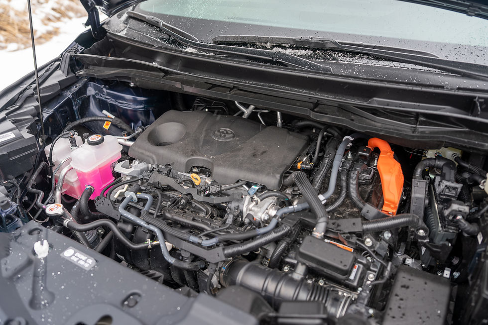 Toyota Sienna Hybrid - Toyota engine bay with pink coolant, orange high-voltage cable, and snow on the windshield in a cold outdoor setting.