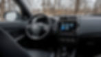 Mitsubishi RVR interior featuring a steering wheel with a logo, a touchscreen displaying apps, and snowy trees visible through the window.