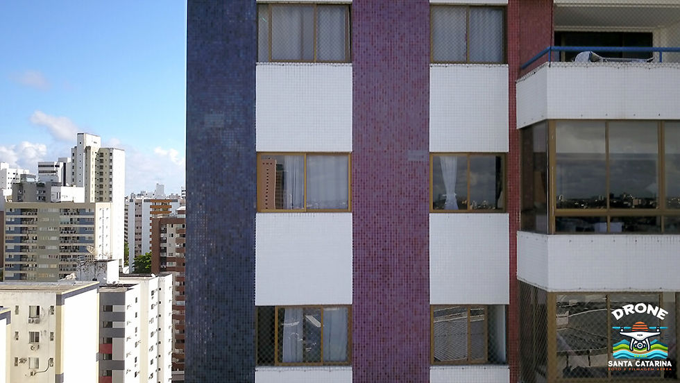 Registro aéreo de um edifício com pastilhas coloridas, destacando possíveis pontos de manutenção na fachada.