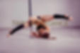 Poledancerin im umgedrehten Spagat an der Stange