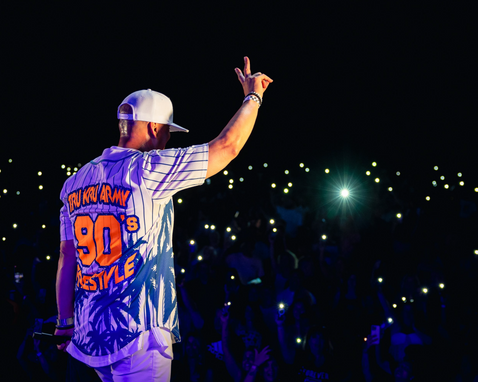  Artist in pinstripe jersey performing under stage lights – Raised Media Co