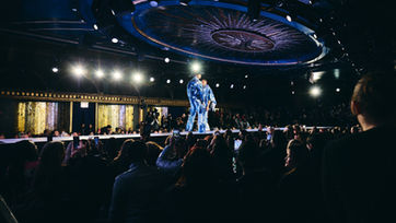 Performer on elevated fashion stage under spotlight – Raised Media Co