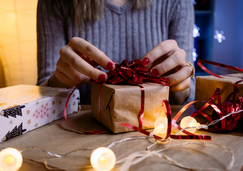 A woman wrapping a Christmas gift with a sparkly bow.