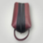 The top view of a handmade burgundy pebble leather men's shaving bag with black leather accent and zipper.