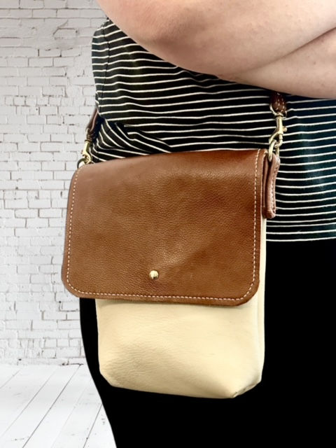 Thumbnail: A person wearing a cream and brown leather shoulder bag.