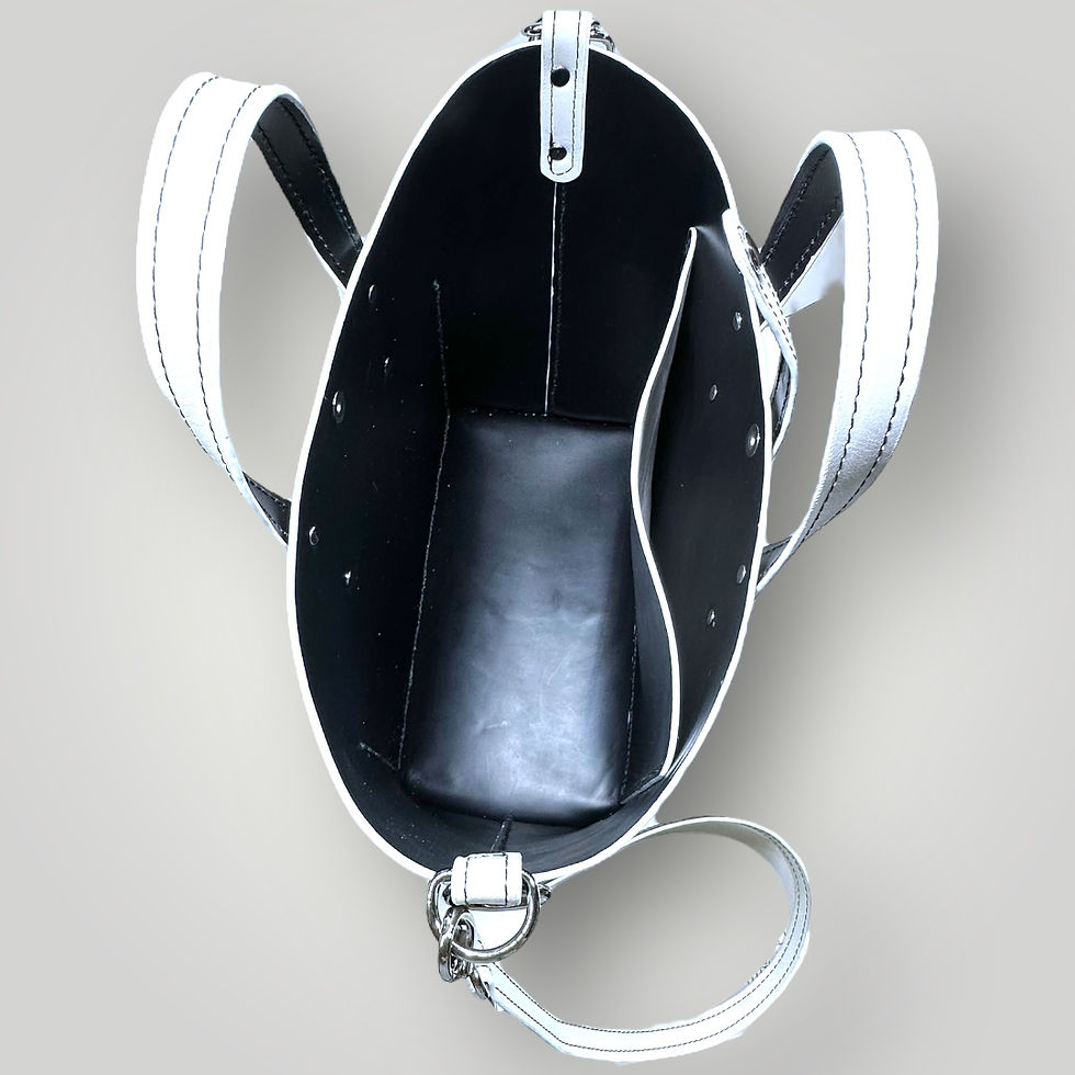 Thumbnail: The inside view of a handmade white leather bag with black interior, matching handles and strap, and silver hardware.