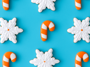 white snowflake cookies and white and orange candy cane cookies on a blue background