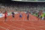 Athletes running on a track in a stadium.