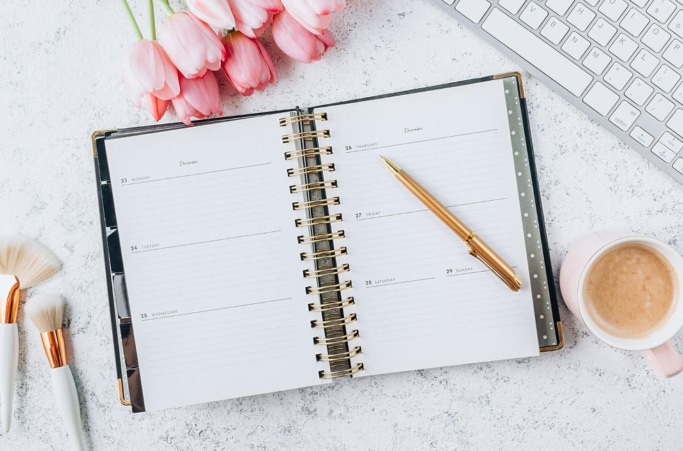 Planner open on desk with gold pen on top.