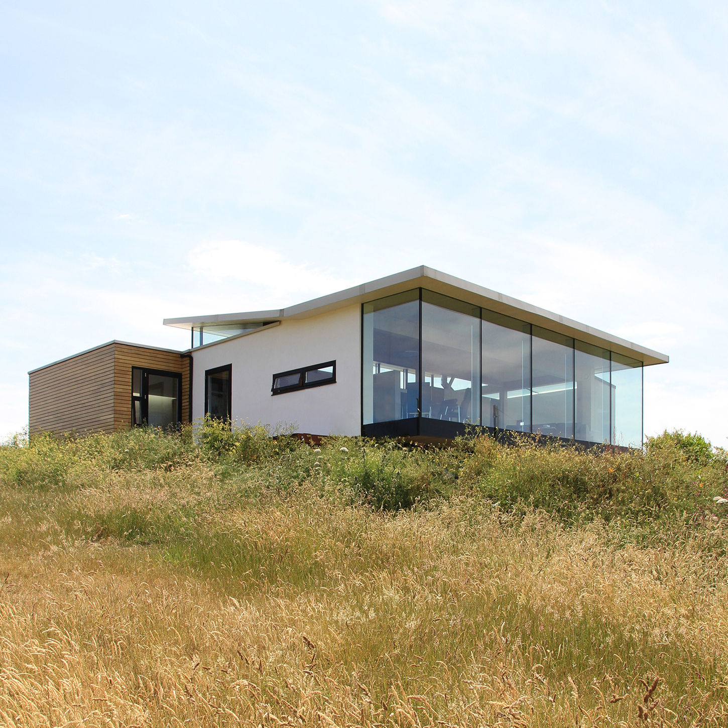 Exterior view of transformation of bungalow just below the west escarpment on Guernsey island, reimagined by Jamie Falla with Prefabricated CLT frame and full height windows
