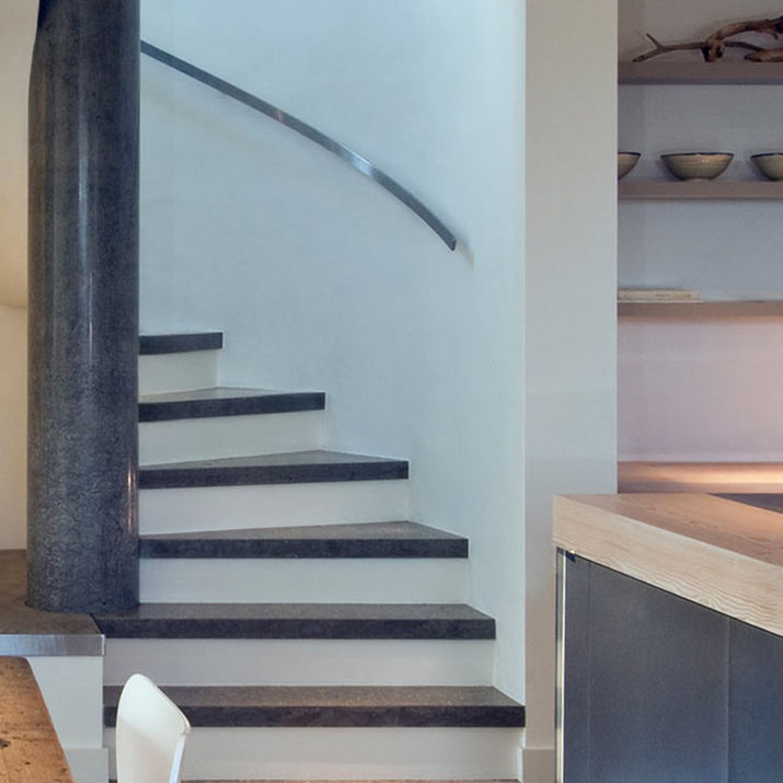 Les Bardeaux interior by Jamie Falla, Guernsey—concrete floor embedded with local beach pebbles. Spiral staircase, Guernsey—sculptural form with polished concrete spine and matching concrete treads