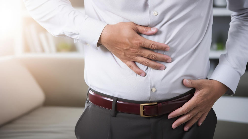 A person in a white shirt and gray pants holds their stomach, appearing in discomfort. Background features a soft light and blurred shelves.